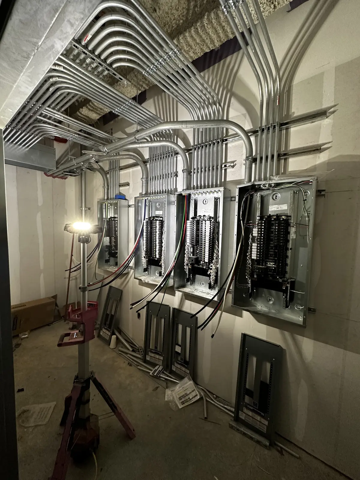 Commercial electrical room with organized EMT conduit entering multiple panelboards