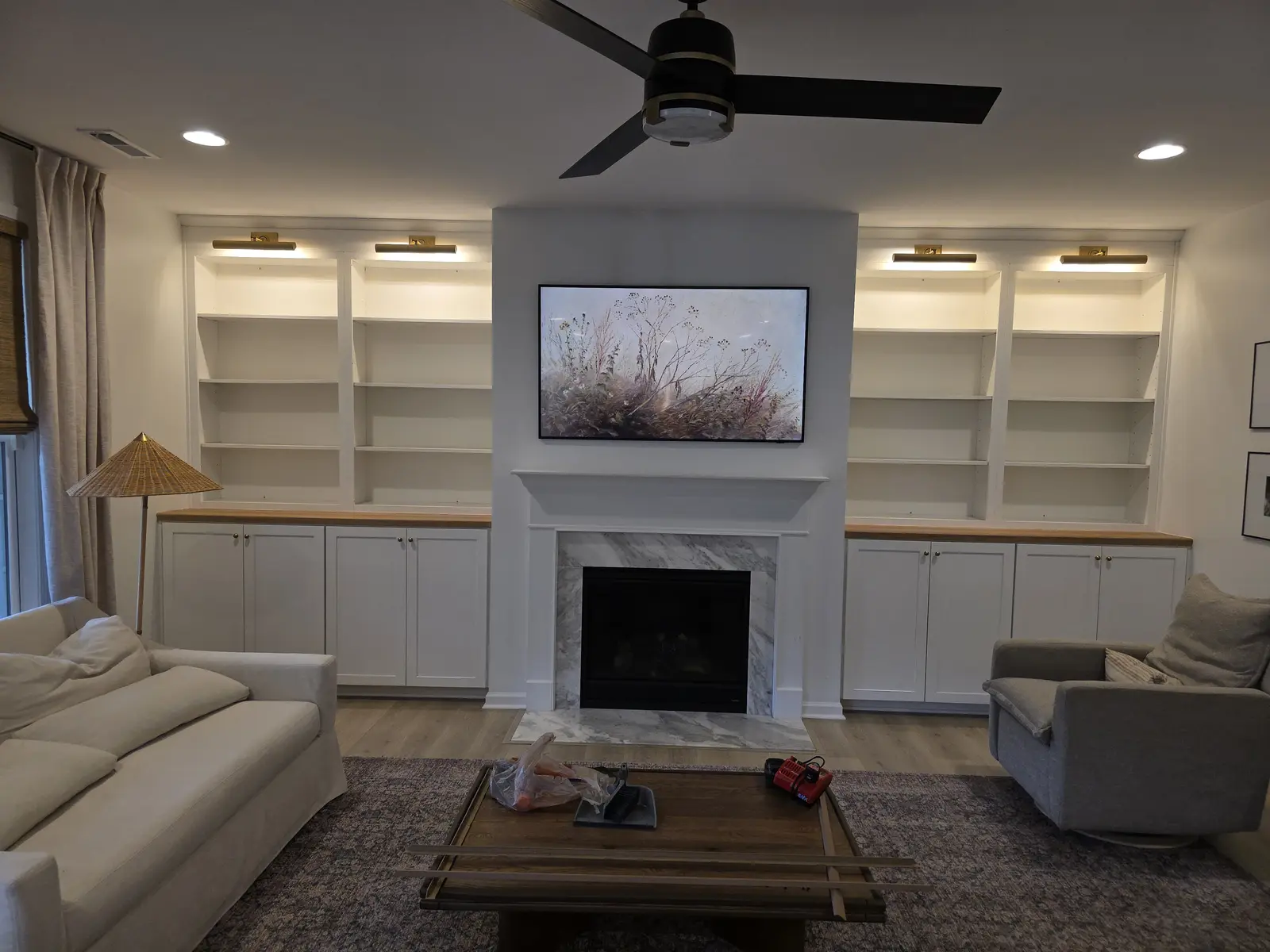 Custom built-in shelving with four brass picture lights